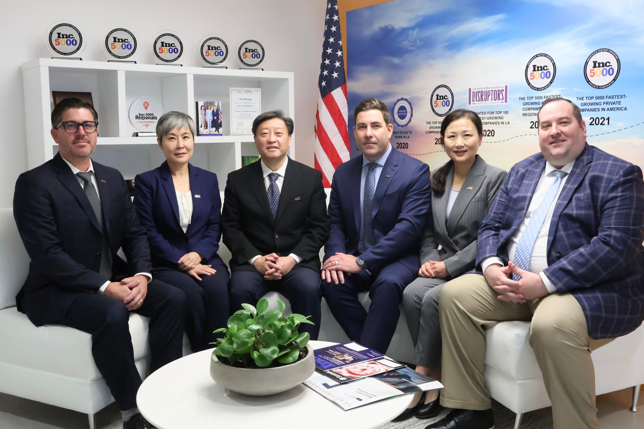 ALC executive leadership team group photo highlighting EB-5 investment expertise, job creation projects, and U.S. investment success, with Inc. 5000 awards in the background.